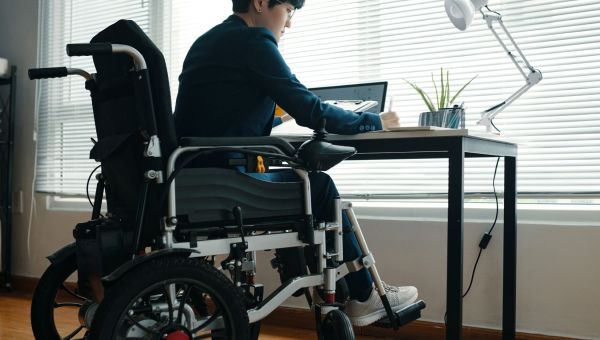 Young entrepreneur in wheelchair working at desk 